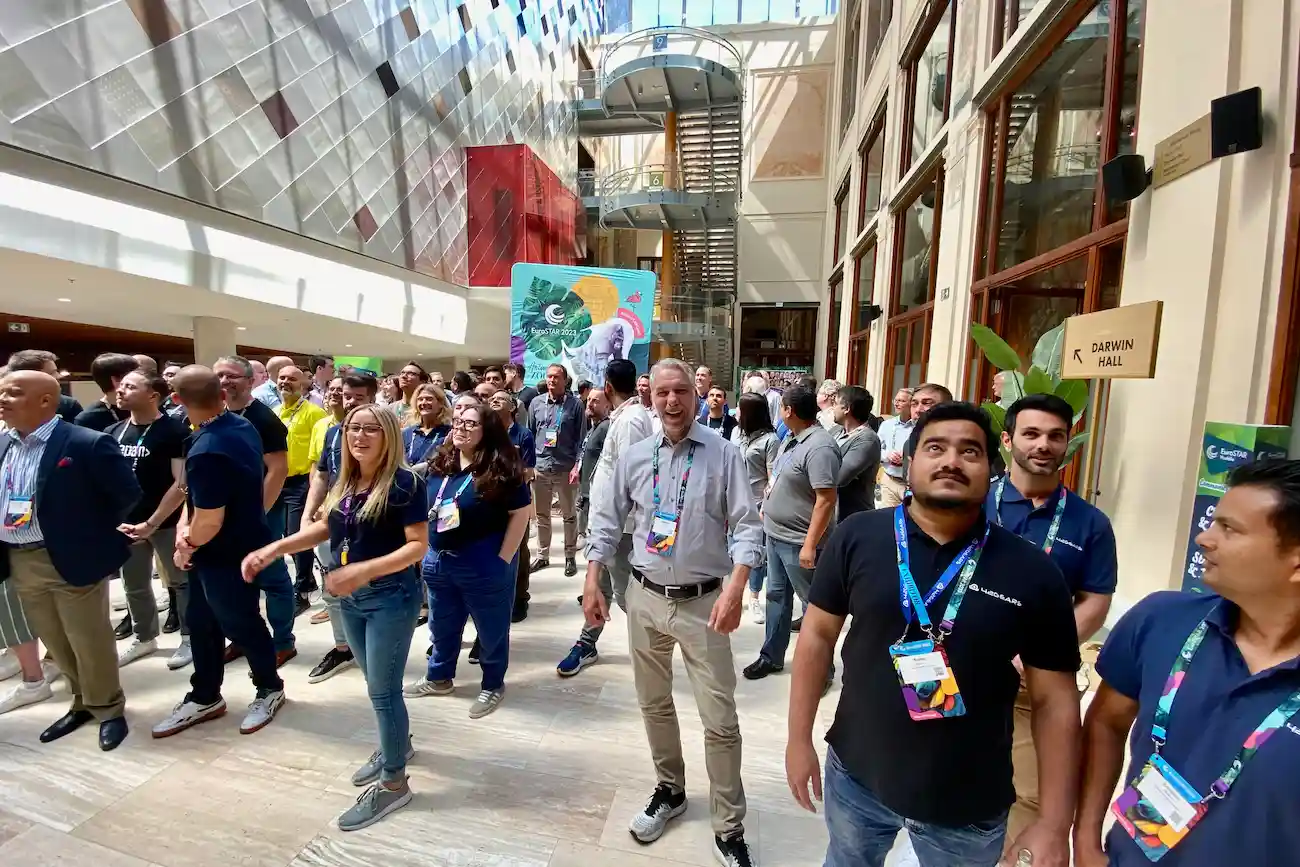 Teilnehmende der EuroSTAR Conference stehen in einer lichtdurchfluteten Messehalle in lebendigem Austausch – die führende Fachkonferenz für Software Testing, QA und Testautomatisierung in Europa.