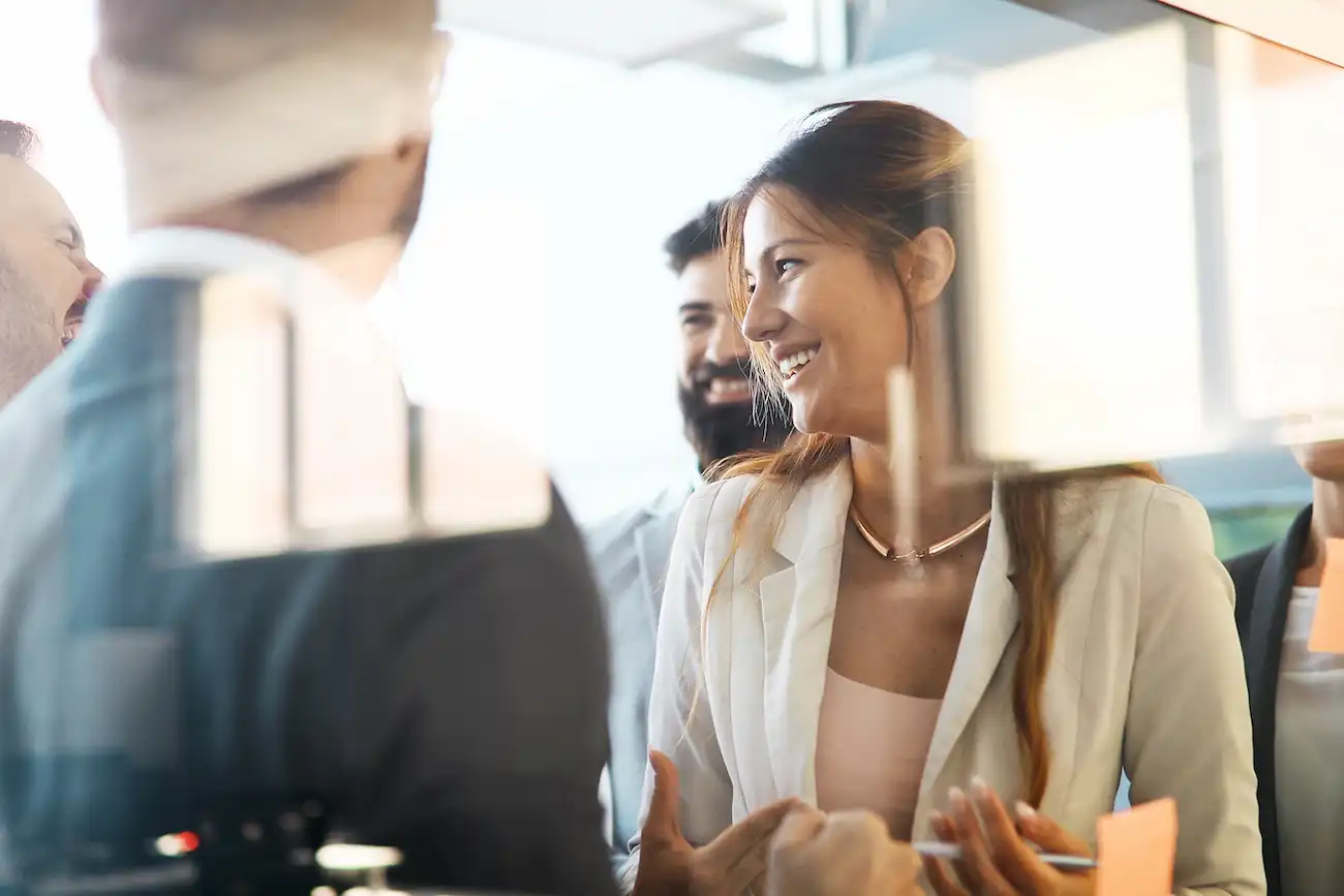 Gruppe von Berufstätigen bei einem Meeting vor einem Whiteboard mit Post-its, die ein kollaboratives UX- oder Design-Thinking-Setting darstellen – ideal zur Veranschaulichung von Human Insight und empathischer Nutzerforschung.